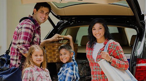 Smiling family of four at the back of the car -Learn more about the Insurance Products and Services we offer