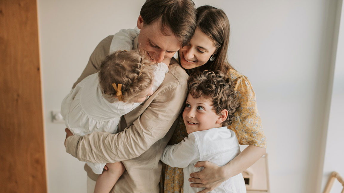 Young family of four hugging each other - Free Insurance Quotes - Contact Us now